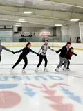 Group of young figure skaters holding hands skating.