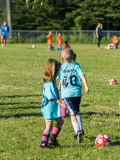 Kids kicking around the soccer ball on field. 
