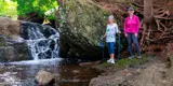 Two females standing beside waterfall on qplex trail.