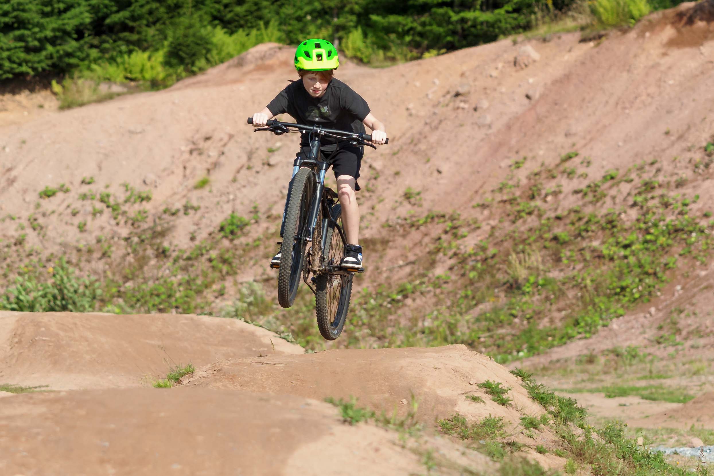 Boy riding bike through dirt mounds and hills.