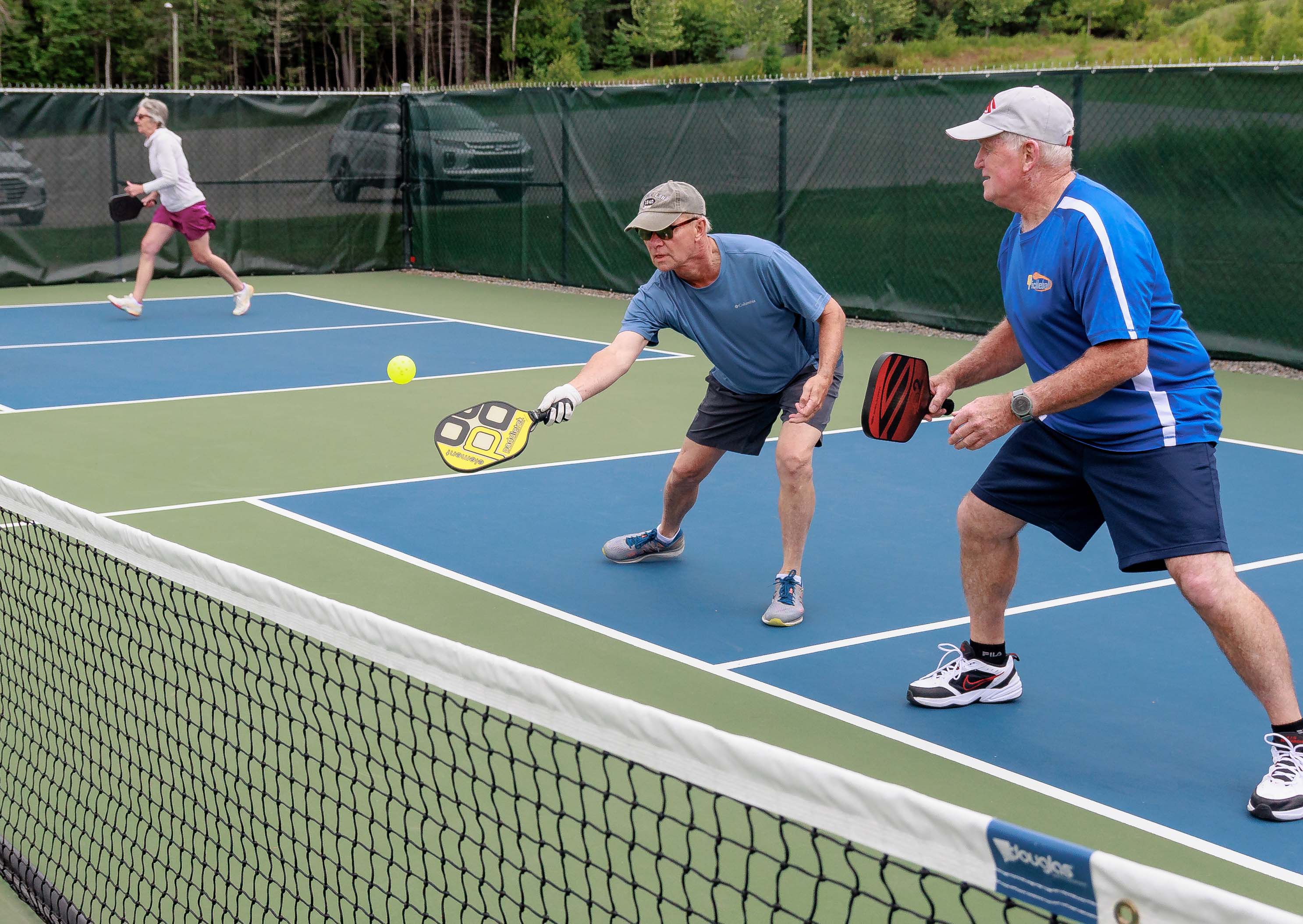 Man and partner hitting pickleball with paddle.