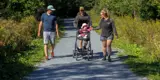 People walking on gravel trail pushing baby stroller.